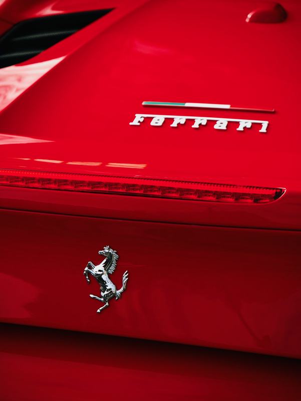 Glossy red paint around a Ferrari rear badge and taillight