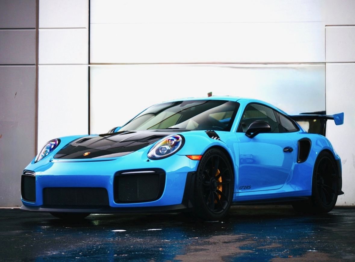 A blue Porsche 911 GT2 RS with a glossy finish, parked on wet pavement