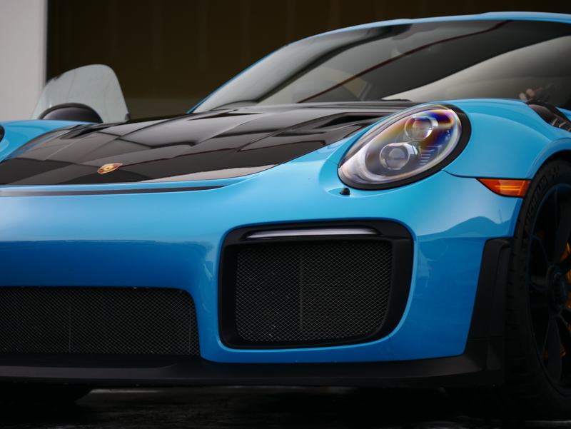 Front close-up of a blue Porsche GT2 RS with a glossy carbon hood and headlight
